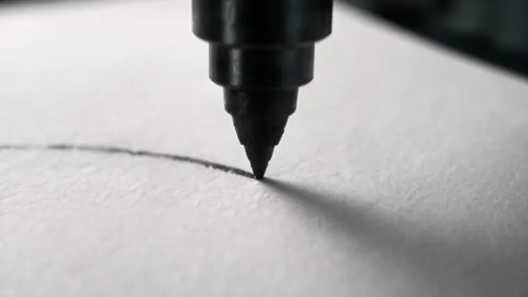 Primer plano de la pluma del robot dibujando sobre el papel, con la textura del papel a la vista