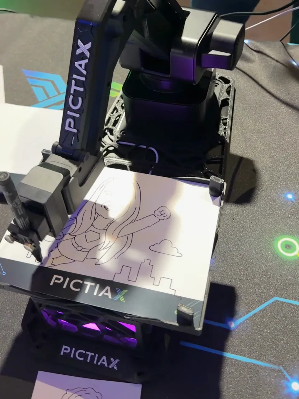 PictiaX® robot arm tracing with a pen the caricature of a person wearing a superhero cape